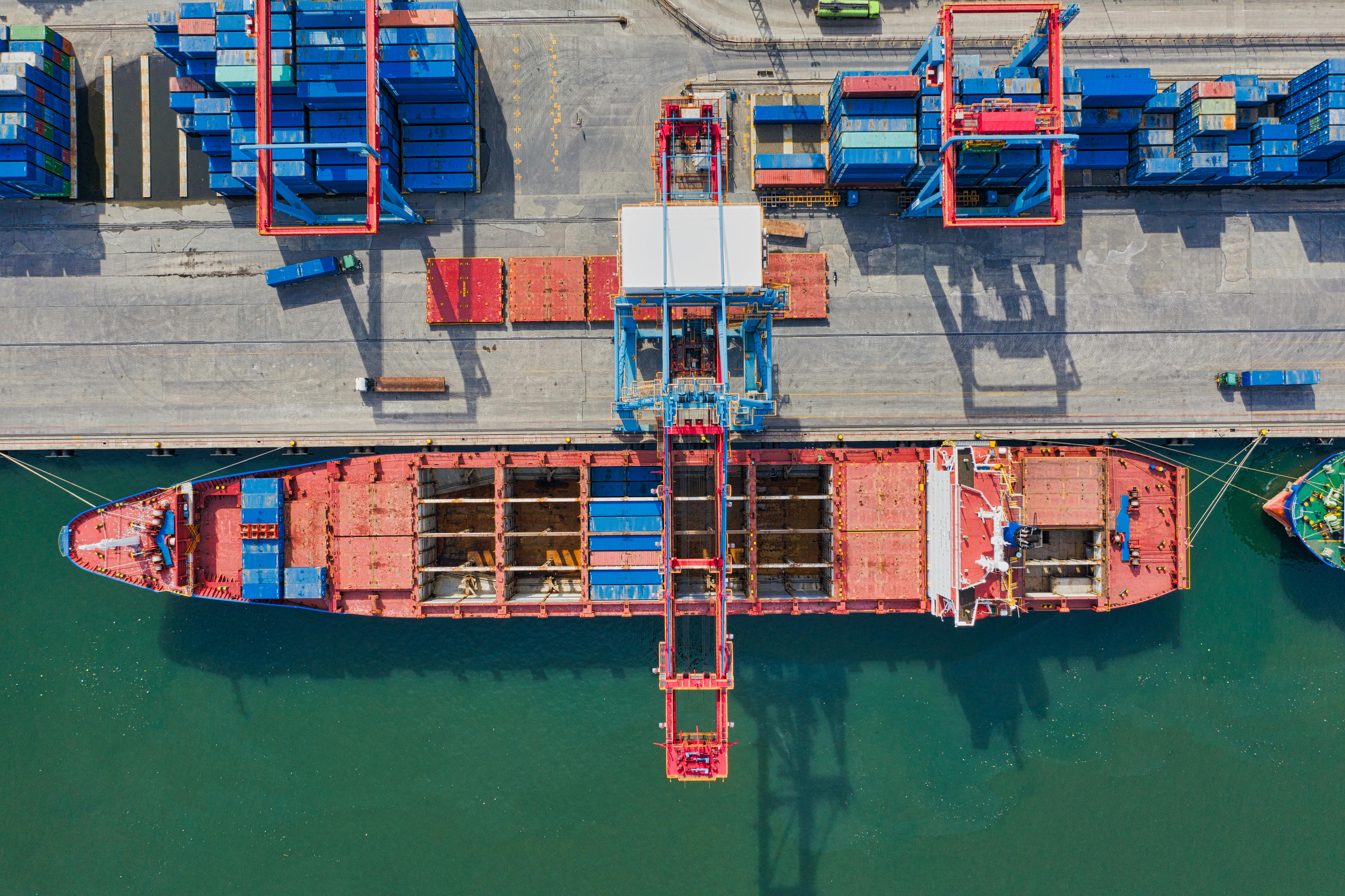 Aerial view of a cargo vessel being loaded with containers by cranes at a port berth